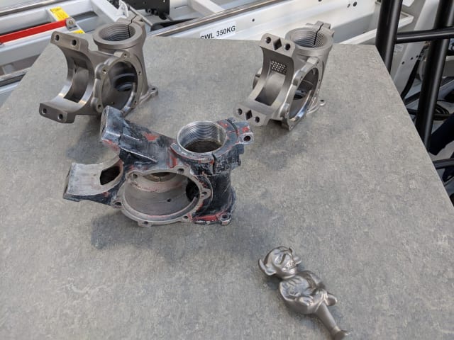 [Siemens’ Materials Solutions site shows an original steering box, center, alongside reverse engineered and 3D printed replicas, as well as a 3D printed hood ornament // Image source: Author]